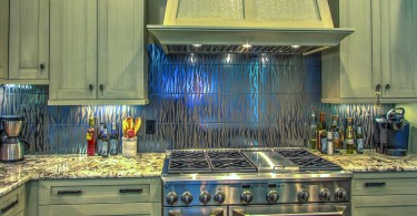 a kitchen with a stainless steel kitchen and silver painted cabinets and drawers. It sits atop a red wood flooring.