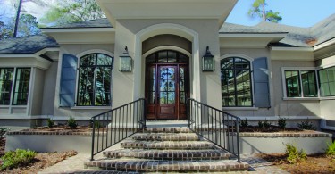 steps lead to wood front door with a large window in its center.