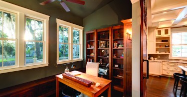 a nook in a home with wood floors, a desk, and wooden shelves. Lots of functional storage space.